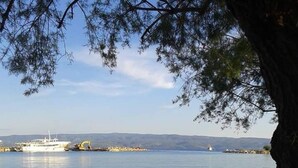 A calm lake with a boat docked on the shore, a sandy beach, and a tree in the foreground. - Apartments Roko (ST) - Economy One Bedroom Apartment with Shared Terrace (A2) (Split)
