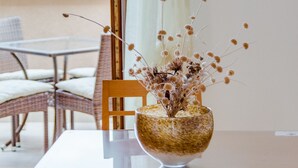 Ein Essbereich mit Tisch, Stühlen und einer Vase mit Trockenblumen.
