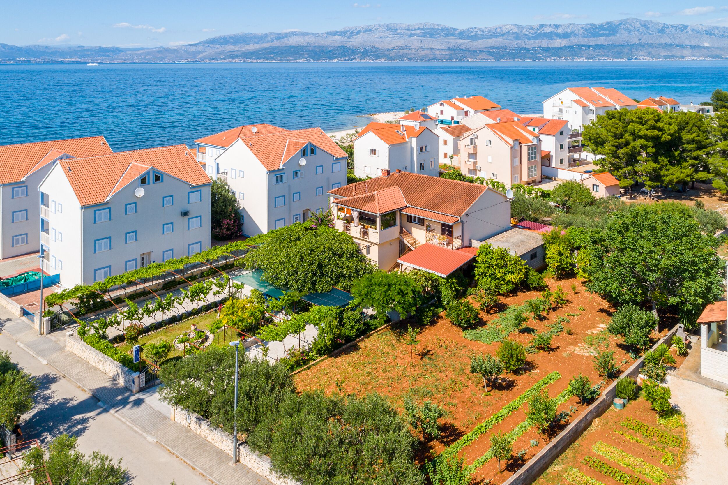 A coastal residential area with white buildings, red roofs, and a clear view of the sea.