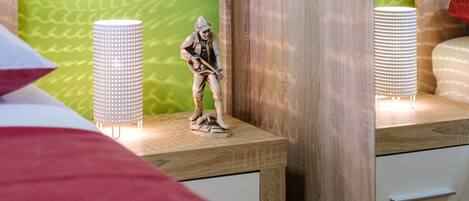 A bedroom with a bed, a nightstand, a dresser, and a small figurine of a person playing a guitar.