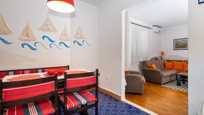 A dining area with a table and chairs, a red pendant light, and sailboat wall art.