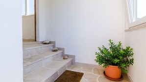 Un escalier avec des marches en pierre, une plante en pot et un petit tapis.
