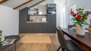 Una cocina moderna con armarios oscuros, una mesa de comedor de madera y un jarrón con flores.