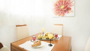 Un tavolo da pranzo con un piatto di frutta, un cornetto e due tazze.