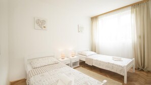 Una camera da letto con due letti, un comodino, una lampada da tavolo e una finestra con tende.