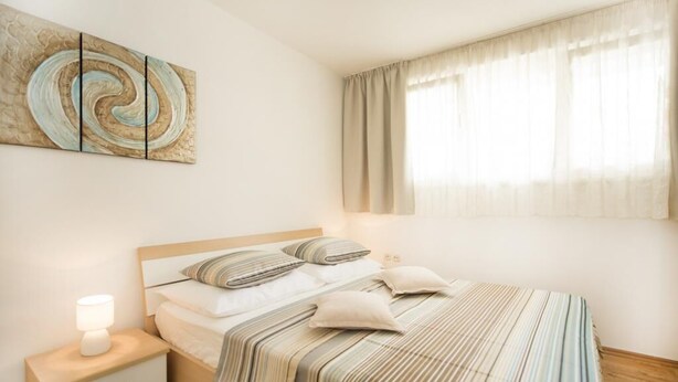 Una camera da letto con un letto, un comodino, una lampada e un quadro appeso al muro.