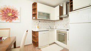 Una cucina compatta con mobili bianchi, forno integrato e lavastoviglie.