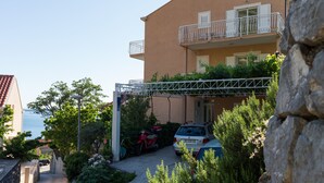 A residential building with a balcony, a parked car, and a scooter. - Villa Dubravka - Superior One Bedroom Apartment with Balcony and Sea View (Mlini)