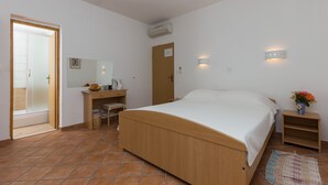 A bedroom with a wooden bed, a bedside table, a nightstand, a mirror, a door, and a wall-mounted light fixture. - Villa Dubravka - Superior One Bedroom Apartment with Balcony and Sea View (Mlini)