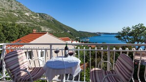 A balcony with two chairs and a table, overlooking a coastal landscape with a view of the sea and hills. - Villa Dubravka - Superior One Bedroom Apartment with Balcony and Sea View (Mlini)