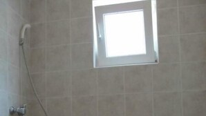 A bathroom with a toilet, a shower, and a small window. - Apartments Boguvila - One-Bedroom Apartment with Terrace (Supetar)
