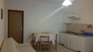 A compact living space with a kitchenette, a dining area, and a sofa. - Apartments Boguvila - One-Bedroom Apartment with Terrace (Supetar)