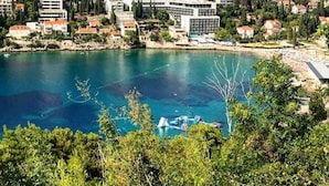 A coastal town with a prominent building near a clear blue sea, surrounded by residential buildings and greenery. - Begović Guest House - Twin Room (Judy) (Dubrovnik)