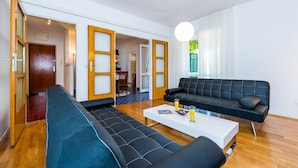 A modern living room with a black sofa, a white coffee table, and a wooden floor. - Apartment Valonija - Two Bedroom Apartment with Terrace and Garden View (Dubrovnik)