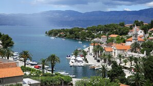 A coastal town with historic buildings, a marina, and mountains in the background. - Apartments Boro - Two Bedroom Apartment with Sea View (A2) (Splitska)