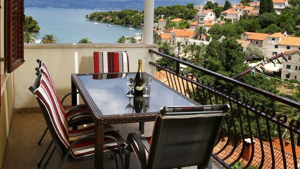 A balcony with a table and chairs, overlooking a lake and a town. - Apartments Boro - Two Bedroom Apartment with Sea View (A2) (Splitska)