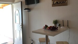 Een moderne keuken met een houten plafond, een flatscreen-televisie aan de muur, een tafel met krukken, en een bord met de tekst 