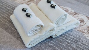 Two neatly folded white towels with black tags on a patterned fabric surface. - Guest House Nikolina - Double Room with Balcony and Sea View(1) (Dubrovnik)
