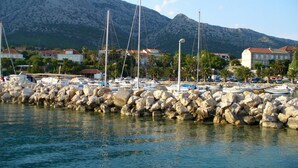 A marina with boats docked, a rocky breakwater, and buildings in the background. - Apartment D & D Orebić - Three Bedroom Apartment with Terrace and Sea View (Orebic)