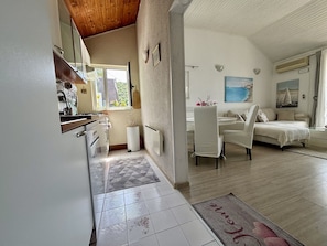 Une cuisine moderne avec un plafond en bois, un coin repas avec une chaise blanche, un canapé et un tableau au mur.