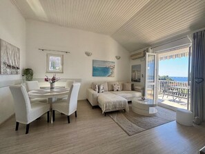 Een moderne woonkamer met een eethoek, een zithoek en een balkon met uitzicht.