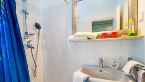 Ein Badezimmer mit einer Badewanne, einem Waschbecken, einem Spiegel und einem Ablagefach mit Toilettenartikeln.
