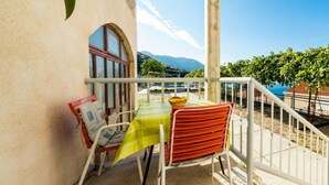 A balcony with a table and chairs, a window, and a view of the sea and mountains. - Apartments Klis -Studio Apartment with Terrace - 2 (B) (Soline)
