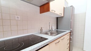 Une cuisine moderne dotée d’une cuisinière intégrée, d’un évier à deux bacs et d’un réfrigérateur en acier inoxydable.