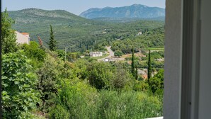 A view of a mountainous landscape with a winding road, buildings, and greenery.
