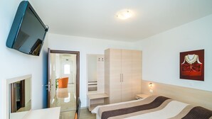 A modern hotel room with a bed, a TV mounted on the wall, a wardrobe, and a painting on the wall. - Villa Samba - Two-Bedroom Apartment with Terrace and Sea View (Mlini)