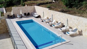 A swimming pool with lounge chairs and umbrellas, surrounded by stone walls and greenery. - Villa Samba - Two-Bedroom Apartment with Terrace and Sea View (Mlini)