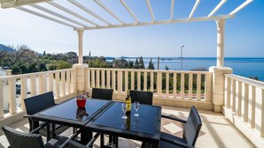 A terrace with a table and chairs, a bottle of wine, and a view of the sea. - Villa Samba - Two-Bedroom Apartment with Terrace and Sea View (Mlini)