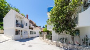 Un edificio blanco con un balcón y un árbol en primer plano.