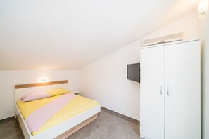 Une chambre à coucher avec un lit, une armoire et un téléviseur fixé au mur.