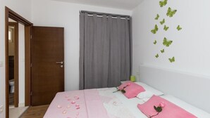 Un dormitorio con cama, puerta, cortina y adhesivos de pared con mariposas.