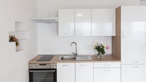 Una cocina moderna con armarios blancos, un lavamanos de acero inoxidable y un horno empotrado.