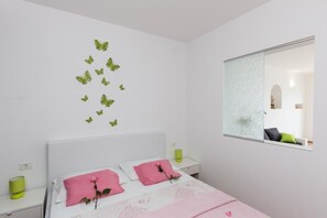 Ein Schlafzimmer mit einem Bett, zwei Nachttischen, einem Spiegel und Wanddekorationen mit Schmetterlingen.