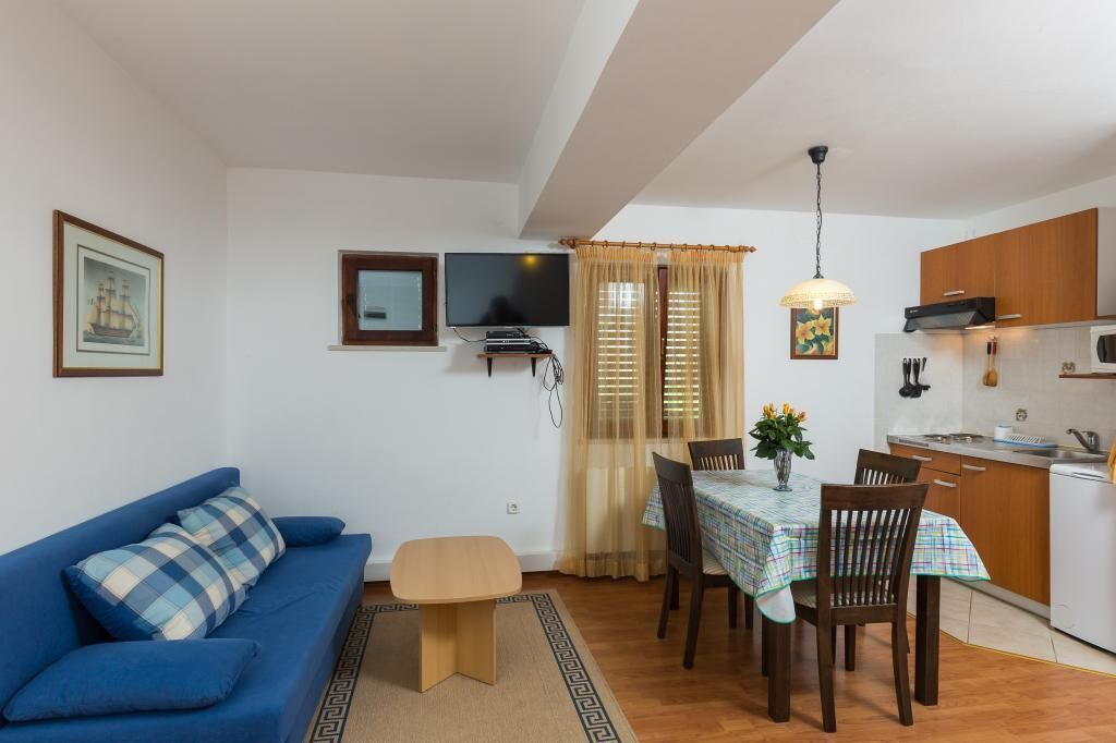 A compact living space with a sofa, a dining table with chairs, a TV, and a kitchen area.