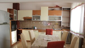 A compact kitchen with a dining area, equipped with a refrigerator, oven, and a table set for four. - Apartments Sweet Life - Three-Bedroom Apartment with Terrace and Sea view (Renata) (ST) (Supetar)