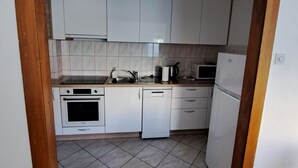 A compact kitchen with white cabinets, a built-in oven, a microwave, and a dishwasher. - Apartment Marko (ST) - Three Bedroom Apartment with Balcony and Garden View (Split)