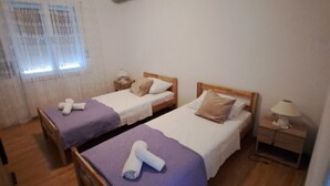 A room with two single beds, a nightstand with a lamp, and an air conditioning unit on the wall. - Apartment Marko (ST) - Three Bedroom Apartment with Balcony and Garden View (Split)