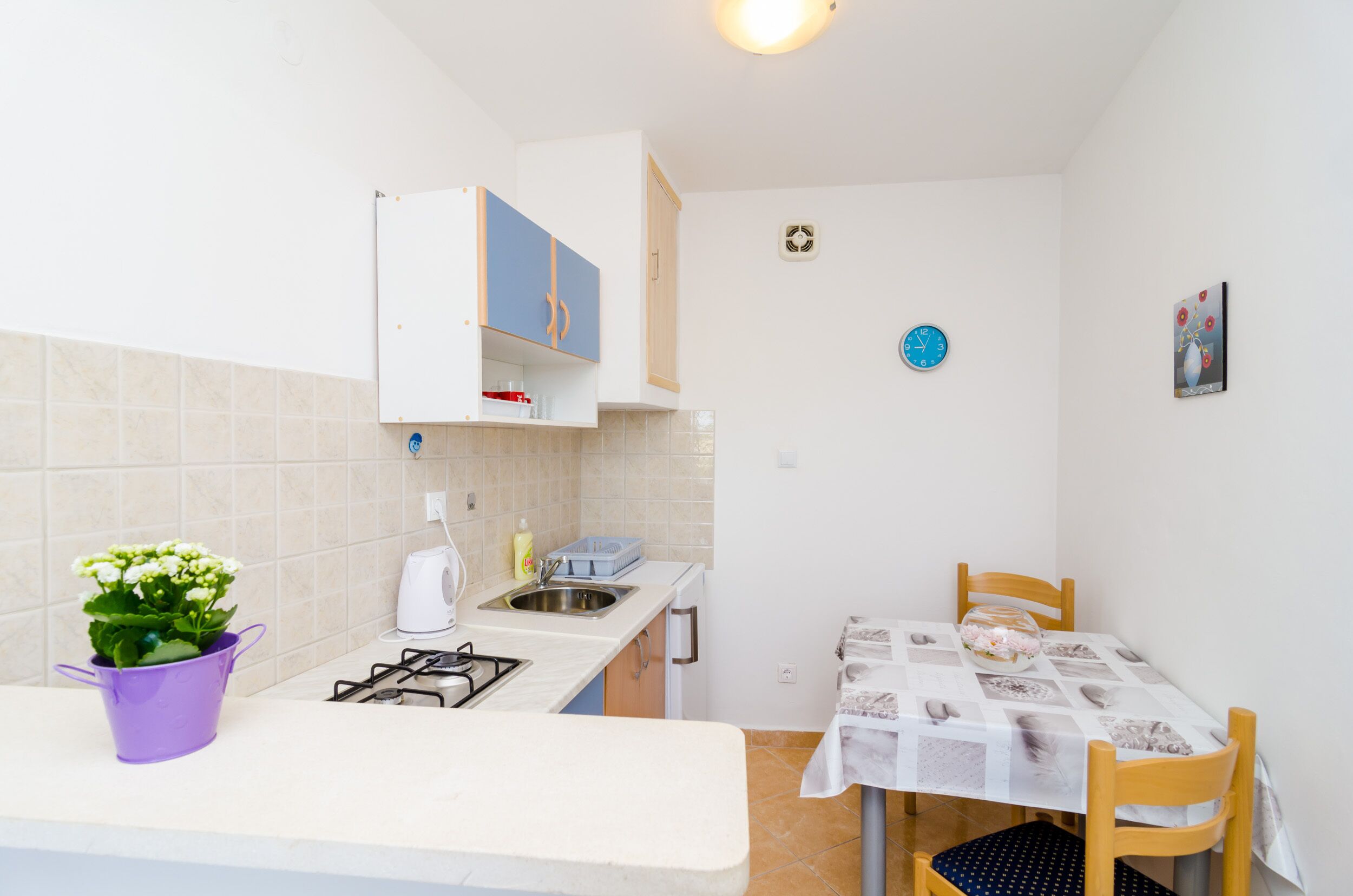 A compact kitchen with a gas stove, sink, and a dining table with chairs.