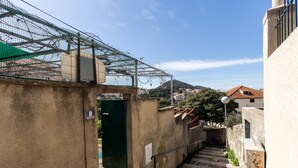 Una escalera estrecha con barandilla de metal, una puerta verde y una pared de concreto con grafitis.