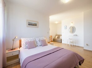 Un dormitorio con cama, mesita de noche, lámpara y un pequeño escritorio con silla.
