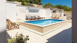 A pool area with lounge chairs, a stone wall, and a clear blue sky. - Villa Lavanda Korčula - Five Bedroom Villa with Pool and Sea View (Korcula)