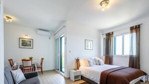 A bedroom with a bed, a sofa, a dining table with chairs, a window with curtains, and a ceiling light fixture. - Villa Lavanda Korčula - Five Bedroom Villa with Pool and Sea View (Korcula)