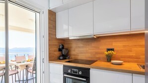 A modern kitchen with white cabinets, a wooden countertop, a coffee maker, and a view of the sea through a glass door. - Villa Lavanda Korčula - Five Bedroom Villa with Pool and Sea View (Korcula)