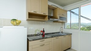Een moderne keuken met lichte houten kastjes, een granieten aanrechtblad en een raam met uitzicht op het platteland.