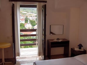Una camera d'albergo con balcone, un letto, una scrivania e un comodino.