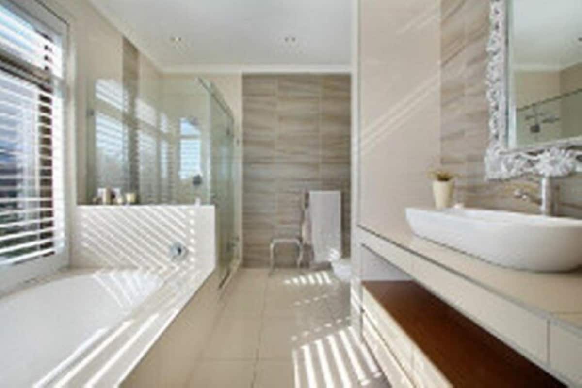 A modern bathroom with a large mirror, a white sink, and a glass shower enclosure.